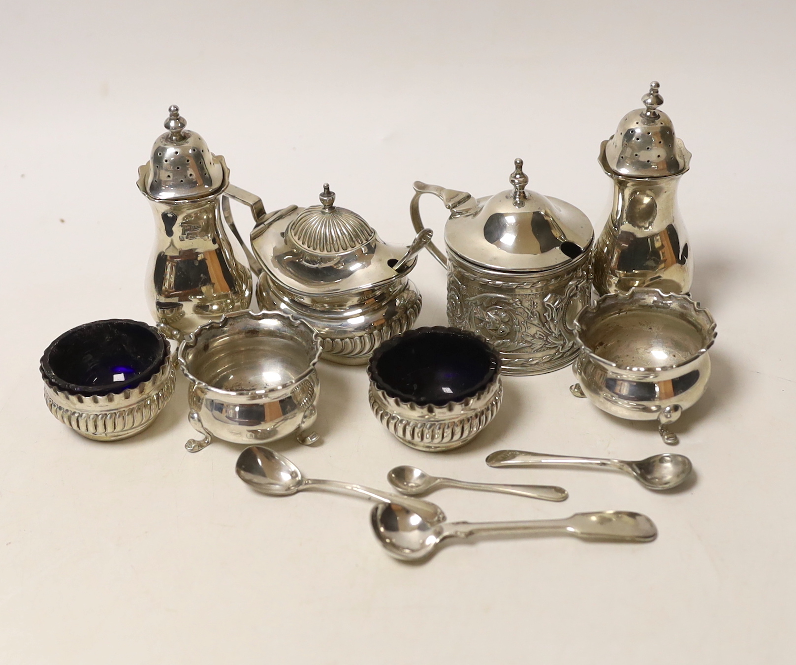 Two pairs of small silver salts, a pair of silver pepperettes, and two silver mustard pots including late Victorian, together with five small spoons (one silver).